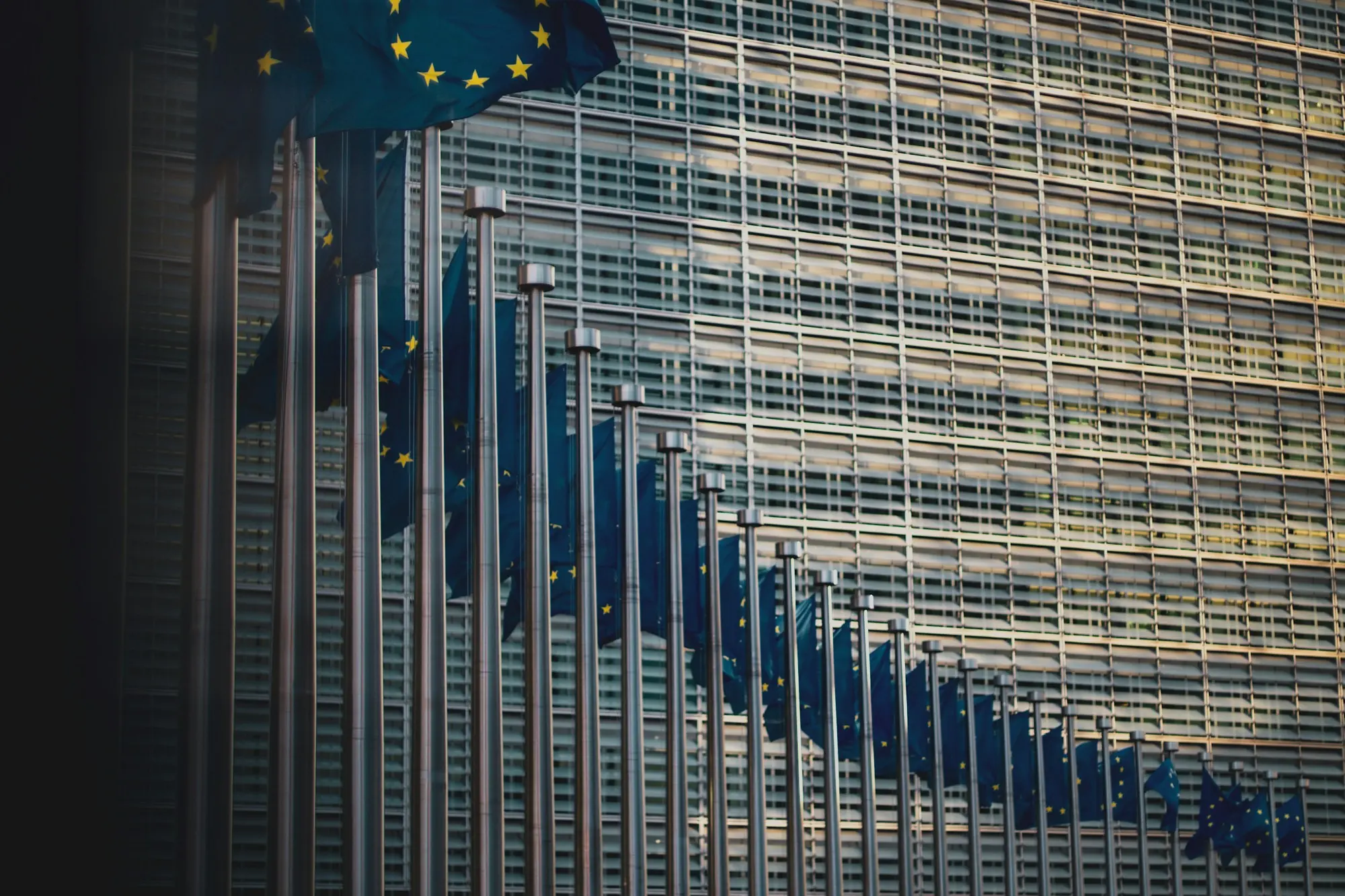 Reihe von Flaggen der Europäischen Union vor der Glasfassade des Berlaymont-Gebäudes in Brüssel